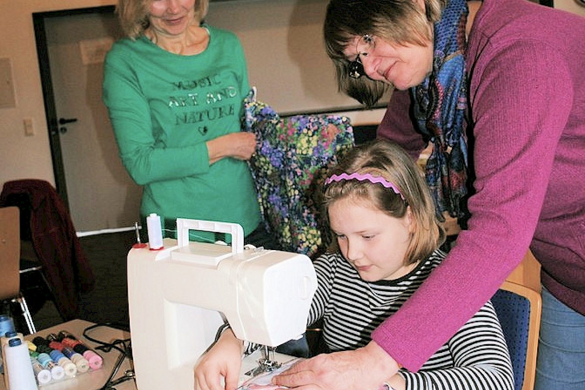 Unterstützt von Elke Röscher (rechts) näht Dorothea (8) für ihre Puppe ein Kleid. Auch Frauen und Männer können sich im Näh-Café helfen lassen, regt Petra Jokiel (links) an.